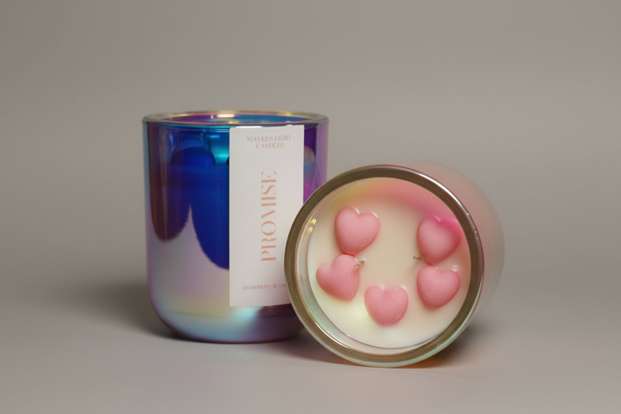 Candle with pink heart design and 'Promise' label on a wooden surface