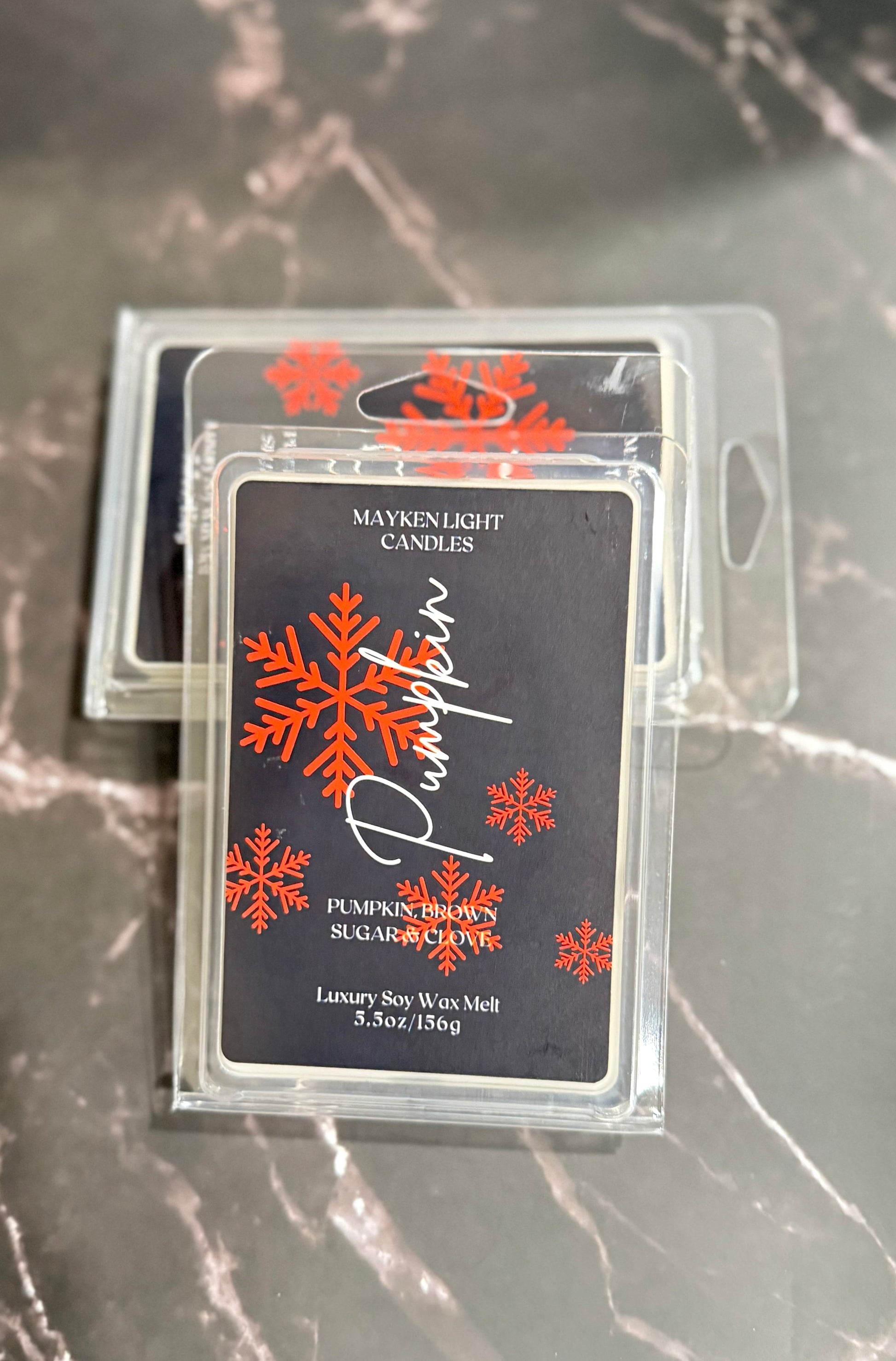 Two wax melt packages with snowflake design on a marble surface