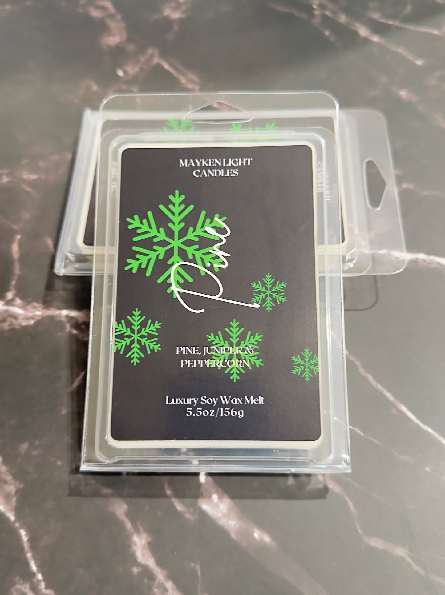 Mayken Light Candles wax melt packaging with green snowflake design on a dark surface