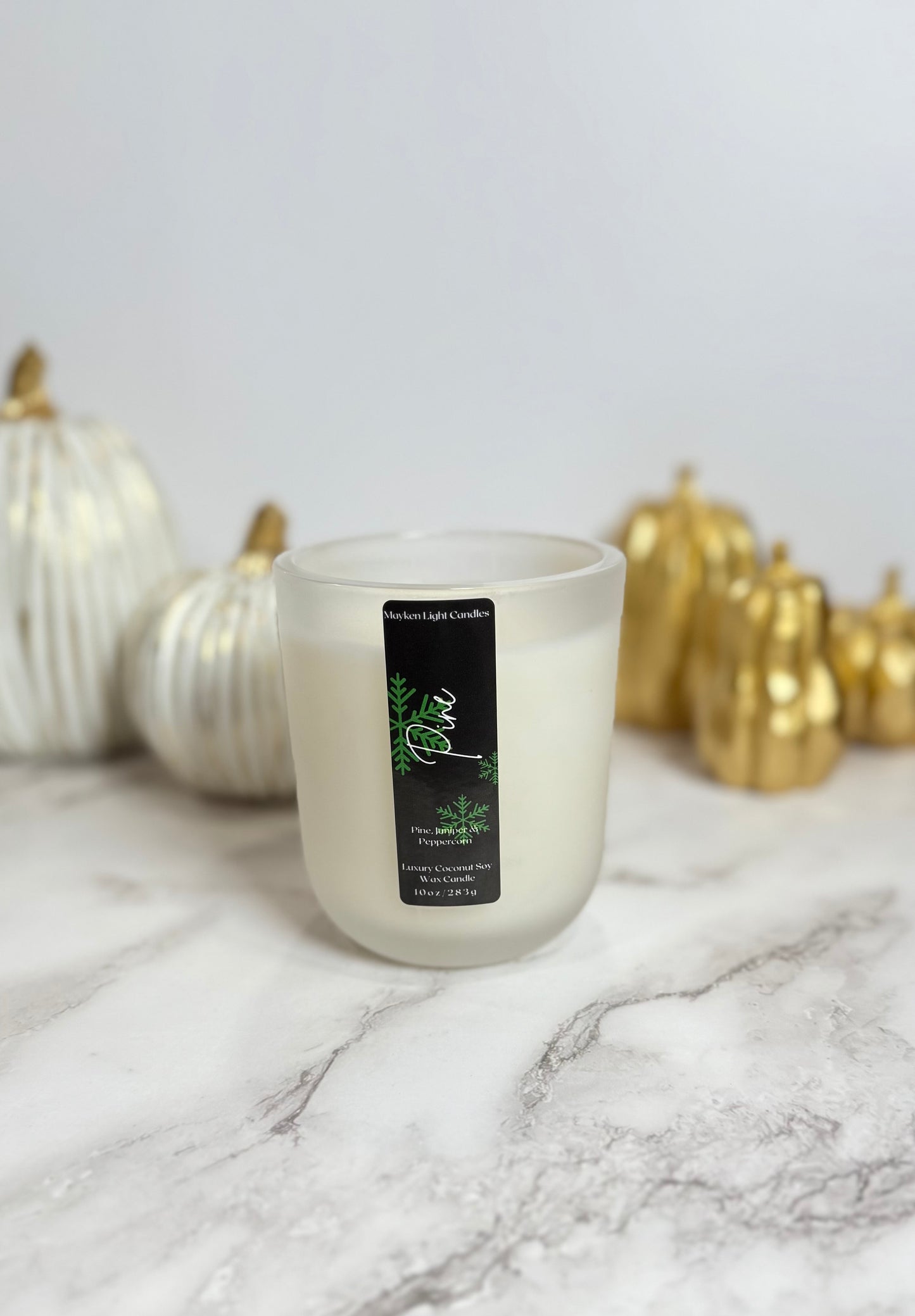 Candle with a label on a marble surface with decorative pumpkins in the background