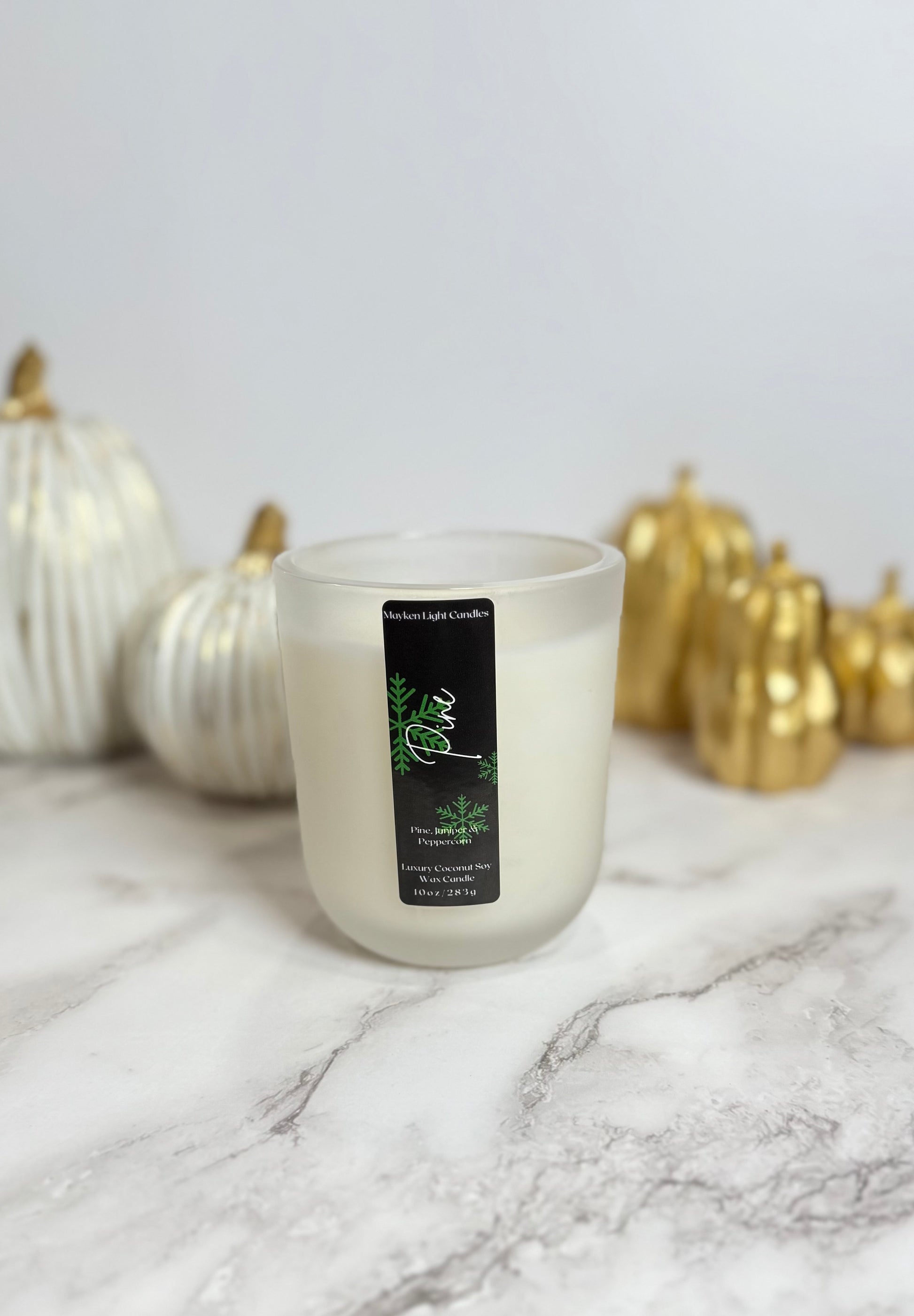 Candle with a label on a marble surface with decorative pumpkins in the background